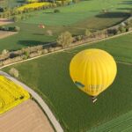 A yellow hot air balloon flies over the green and rural landscape of Empordà, close to the ground. Learn how to describe the purpose of the image (opens in a new tab). Leave it empty if the image is purely decorative.