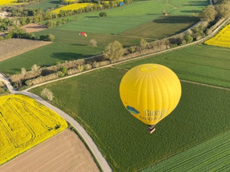 A yellow hot air balloon flies over the green and rural landscape of Empordà, close to the ground. Learn how to describe the purpose of the image (opens in a new tab). Leave it empty if the image is purely decorative.