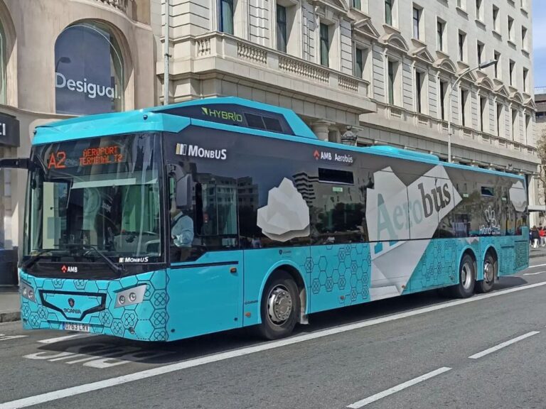 A blue and white Aerobus making a stop on a busy downtown street, facilitating passenger transportation between the airport and the urban core.