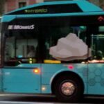 A distinctively colored, sustainable hybrid Aerobus parked at a bus stop, demonstrating a commitment to green mobility in transporting passengers between the airport and the city center.