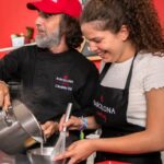 Participant and chef cooking together in a collaborative culinary experience