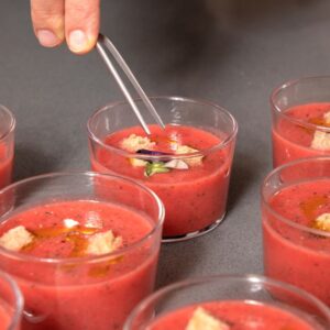 Image of a chef garnishing gazpacho with a decorative flower.