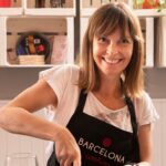 Image of a student skillfully cutting ingredients while enjoying a glass of wine during a cooking class.