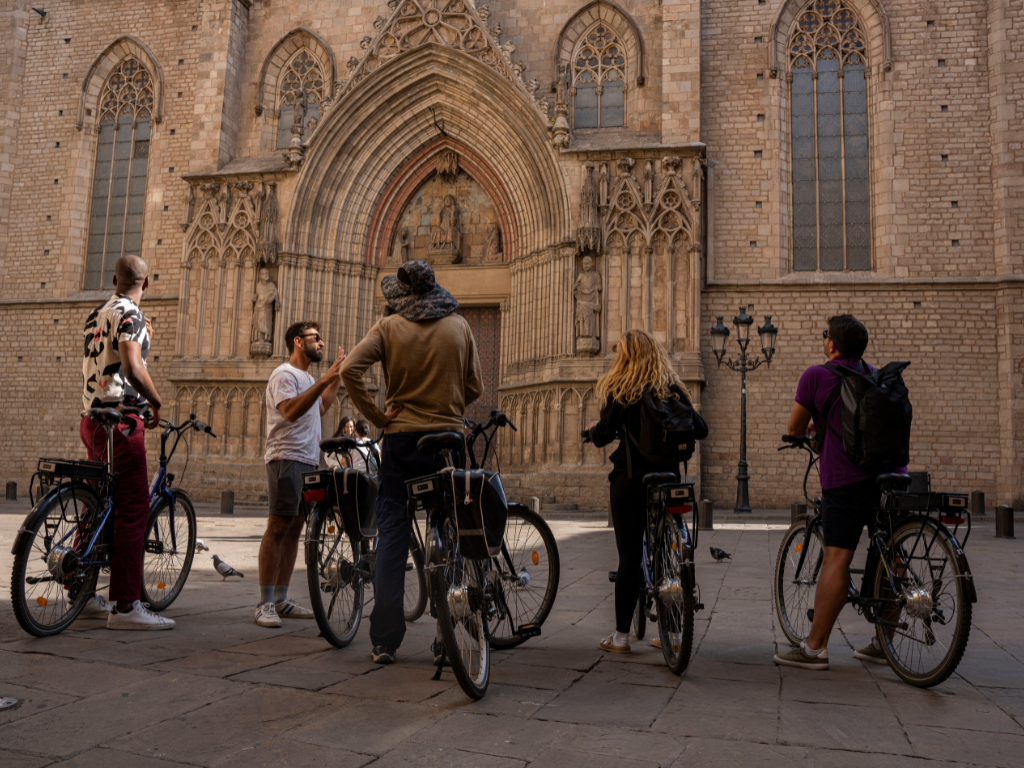 A group of people with electric bikes in front of the Barcelona Cathedral.