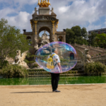 Artistic photo of a man inside a soap bubble at the fountain in Parc de la Ciutadella, Barcelona.