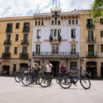 Bikes in the foreground, group behind, and guide talking in Gràcia, Barcelona.