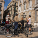 Group receiving explanations next to the Council of Barcelona with some members on e-bikes.