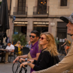 Group members smiling while listening on their e-bikes next to the Council of Barcelona.