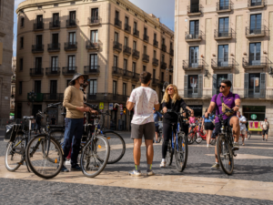 Guide standing and members of the group listening in a plaza in Poble Nou, Barcelona, with bikes.