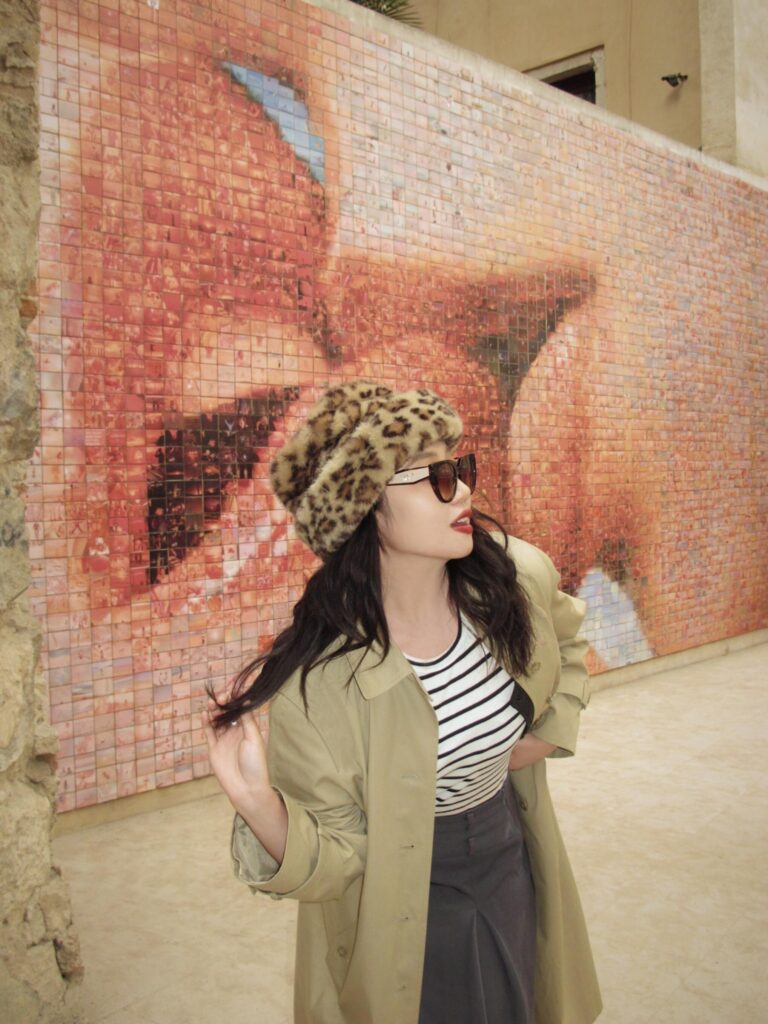 Person posing in front of the "The World Begins with Every Kiss" mural in Barcelona's Gothic Quarter.