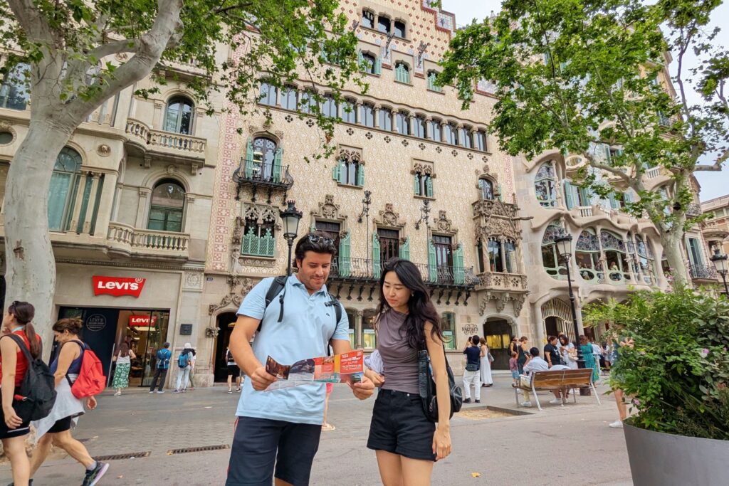 Tourists looking at a map in front of Casa Batlló in Barcelona.